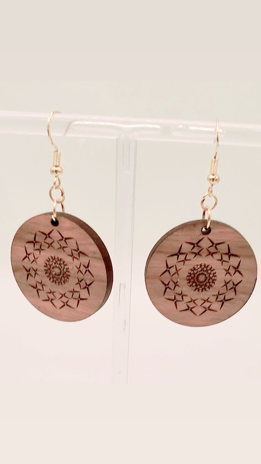 Wooden earrings with starburst patterns on a white background